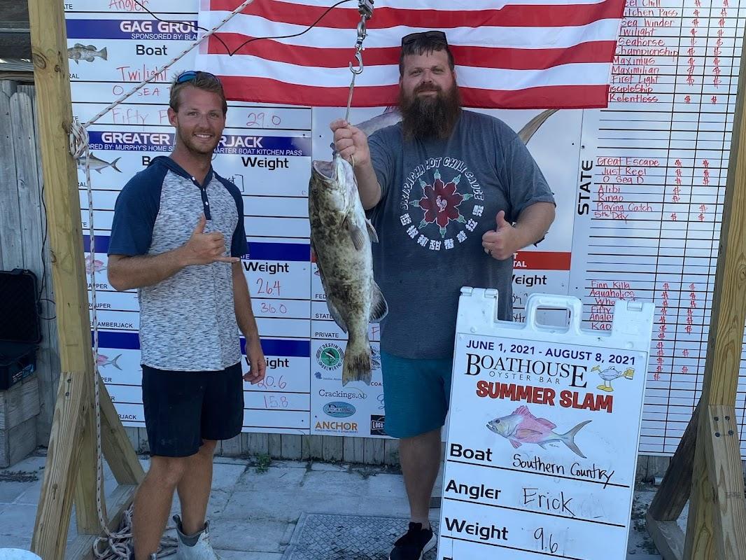 Two anglers weighing a large grouper fish at the Boathouse Oyster Bar Summer Slam tournament in Destin, Florida