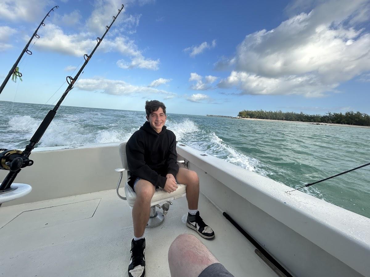 Happy customer aboard Captain Conch Charters fishing boat in Key West waters with fishing rods and turquoise ocean in background