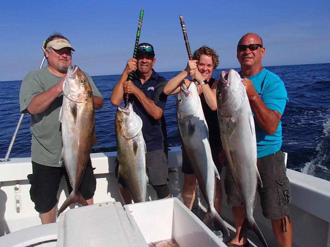 A group of four happy anglers holding up large Amberjack fish on a fishing charter boat in Destin, Florida.