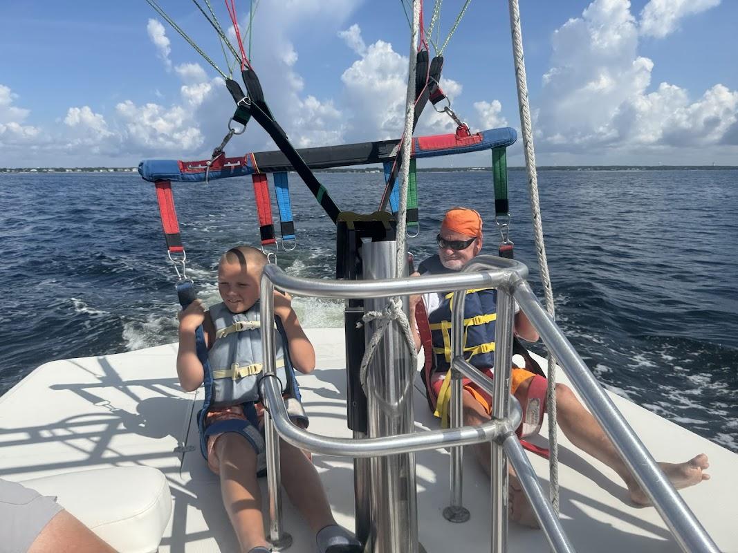 A young boy and a man wearing life jackets and harnesses prepared for parasailing on a boat in Destin, Florida