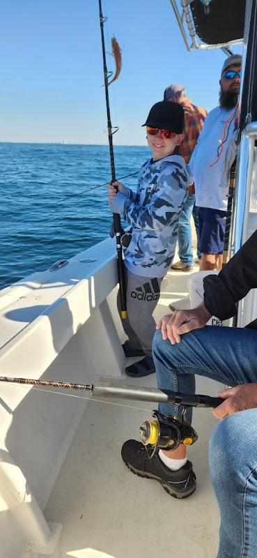 Smiling young boy holding a fishing rod with a catch aboard a Destin Inshore Fishing Co boat