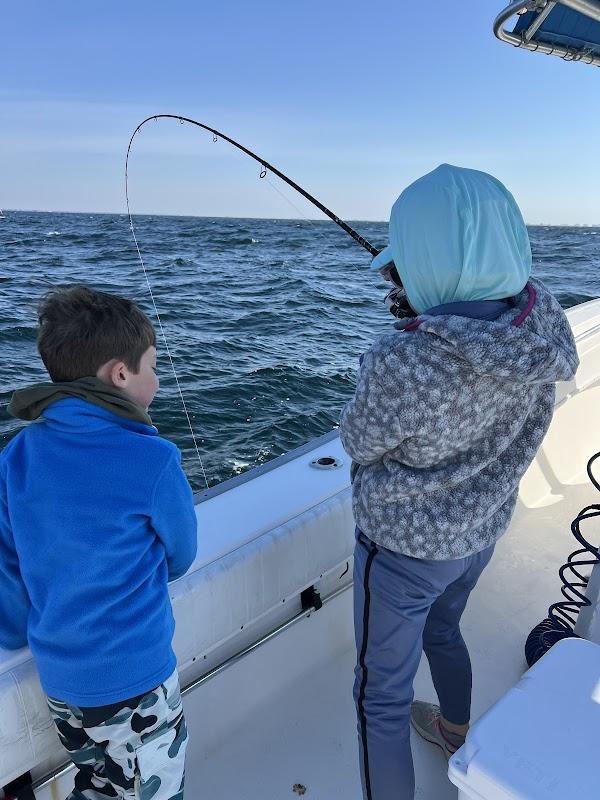 Child and adult fishing from a white boat with fishing rod bent during action on calm blue ocean waters off Destin