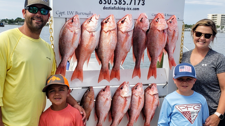 Happy fishing family displaying their fresh catch of red snapper and grouper during a Destin fishing charter