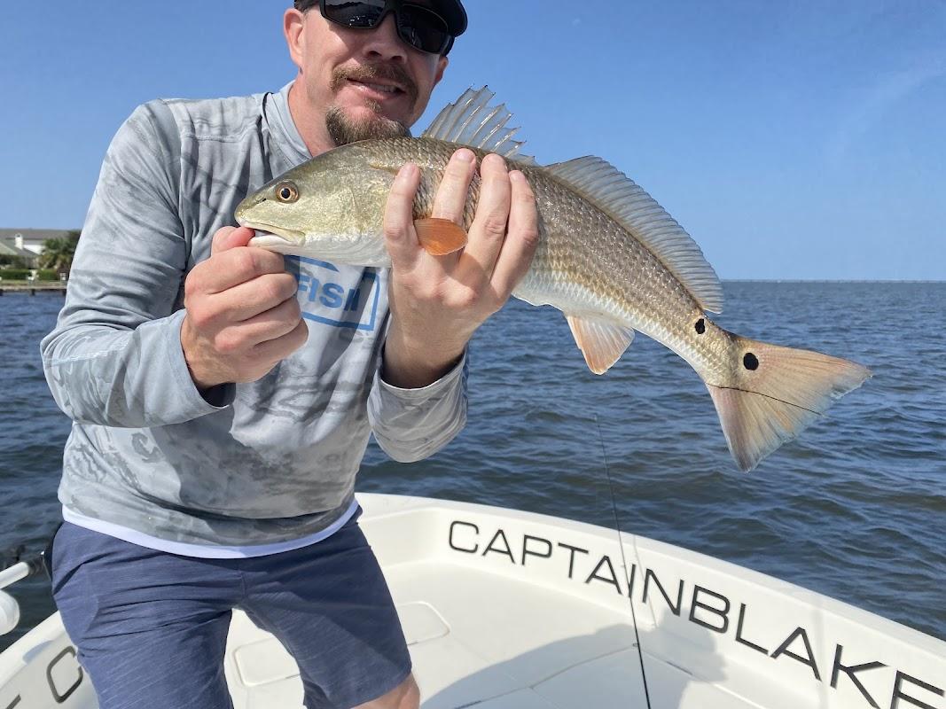 Angler holding a Redfish on a boat labeled Captain Blake with Last Cast Charters in Destin, FL