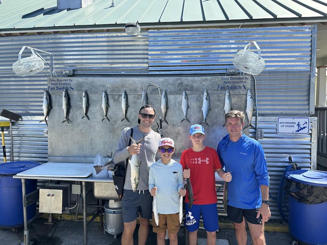 Family group smiling with their catch of Spanish Mackerel at the Last Cast Charters dock cleaning station in Destin, FL