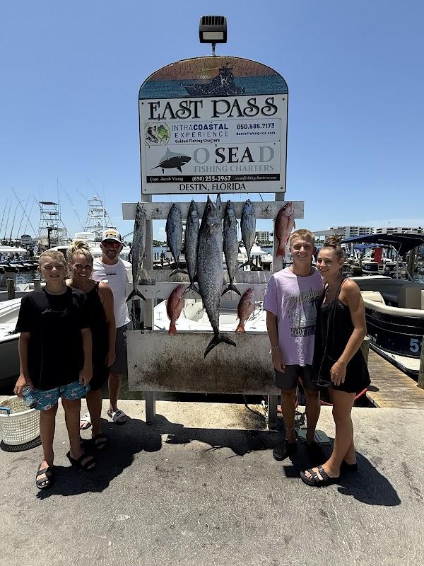 Group photo of a family with a large King Mackerel and Red Snapper catch at the O Sea D Fishing Charters dock sign in Destin, FL.
