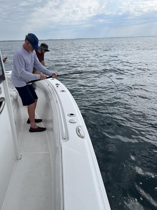 An angler fighting a large fish from the deck of O Sea D Fishing Charters in Destin, Florida.